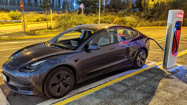 Wide shot of a public fast-charging station with multiple electric cars plugged in during sunset.