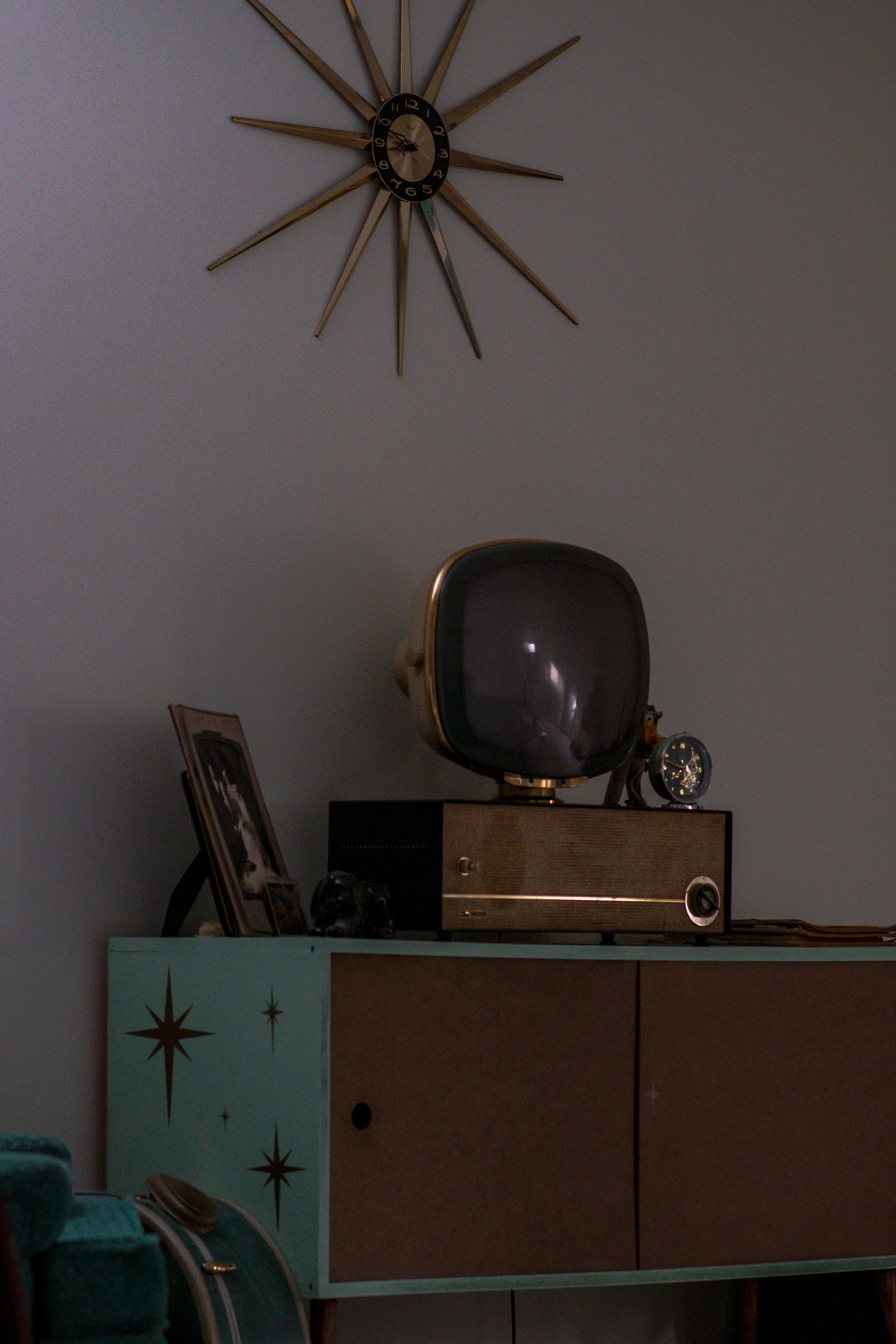 A television sitting on top of a dresser next to a clock