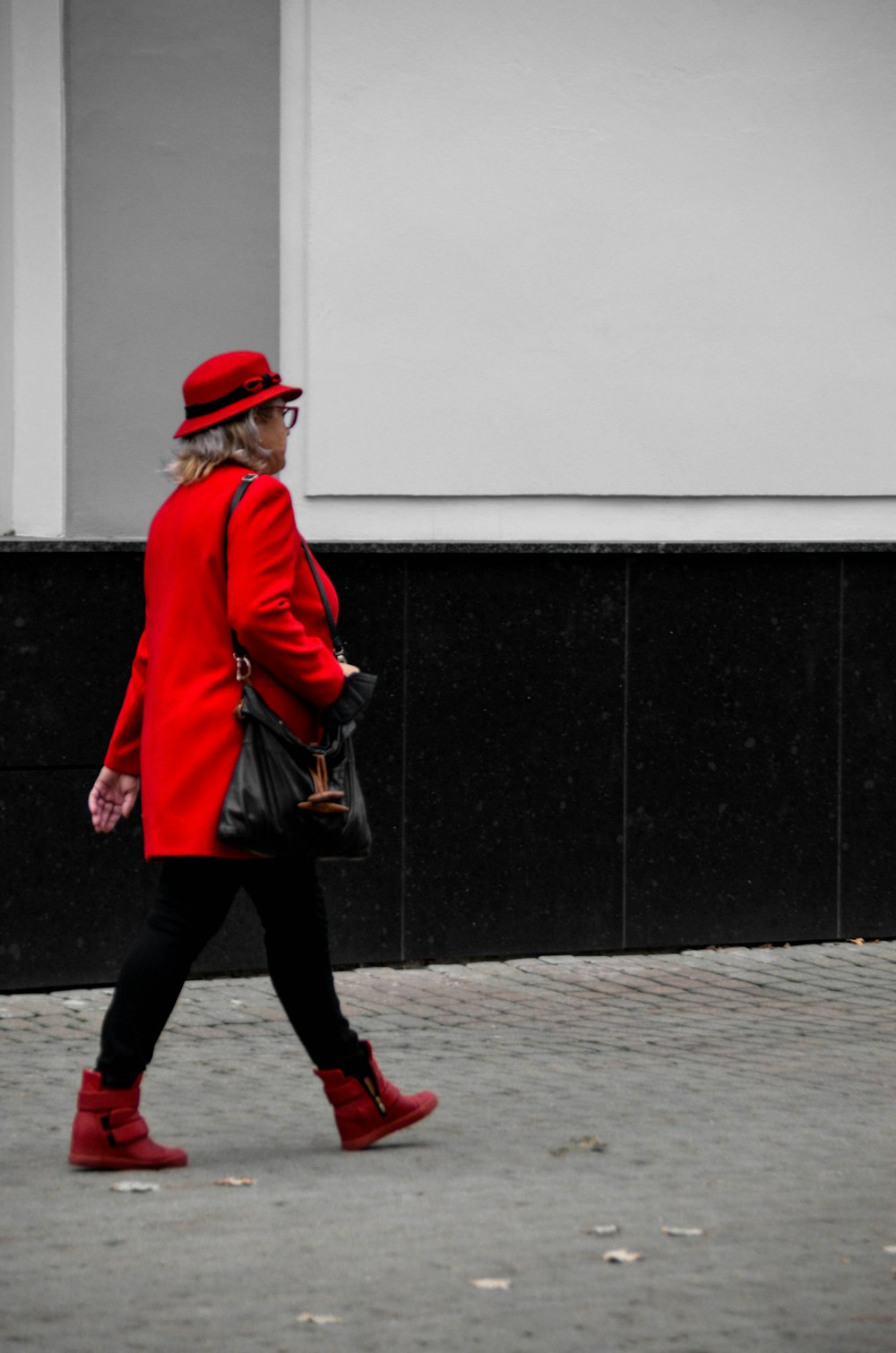 a woman in a red coat is walking down the street