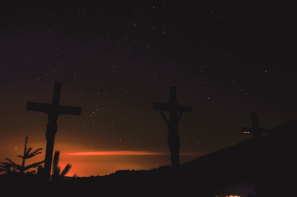 three crosses on a hill under a night sky