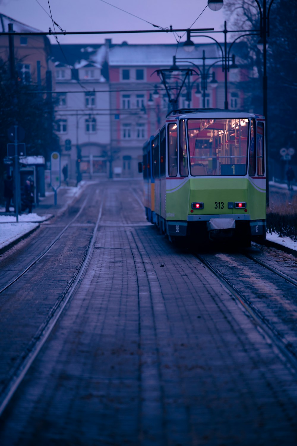 Ein grün-gelber Zug, der die Bahngleise hinunterfährt