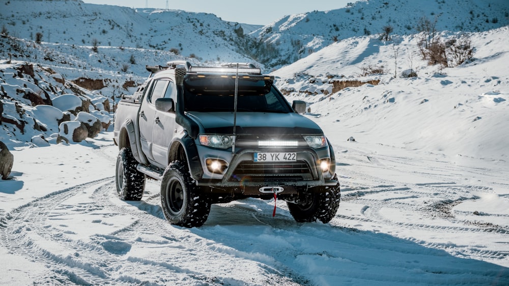 a black truck driving down a snow covered road