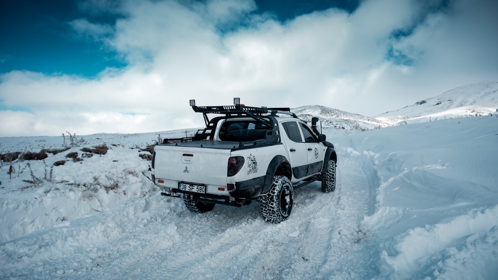 a white truck driving through a snow covered field