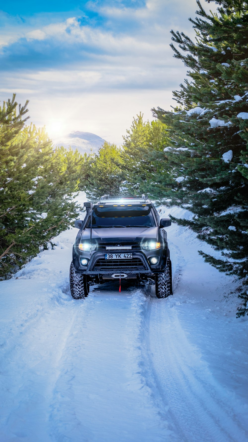 a black truck driving down a snow covered road