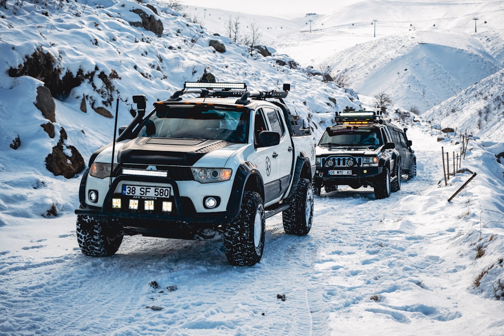 a couple of trucks driving down a snow covered road