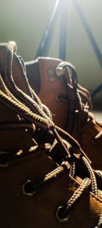 A close-up of stylish men's leather boots resting on a wooden floor.