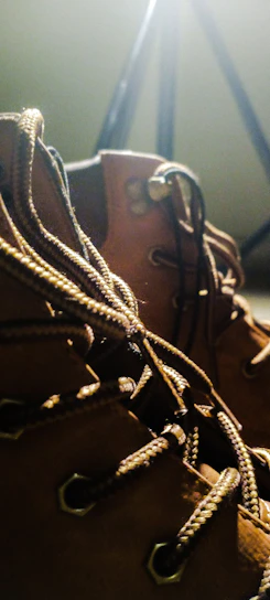 Close-up of sleek black leather boots with matte texture under moody cinematic lighting.