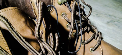 Detail shot of premium football boots laced tightly with shadows playing across the textured leather.