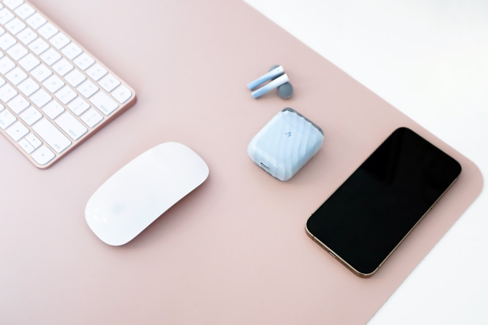 a keyboard, mouse, and cell phone on a desk