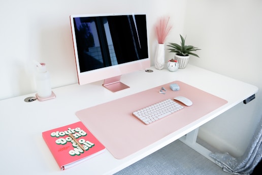 a desk with a computer and a book on it