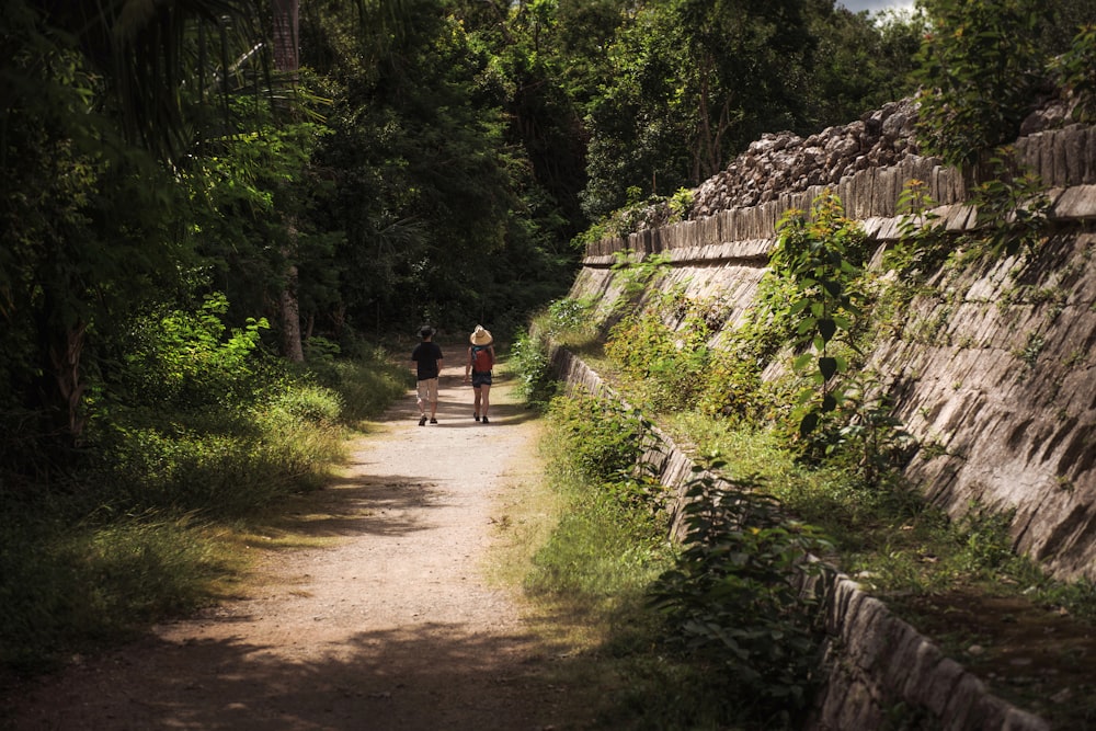 a couple of people walking down a dirt road