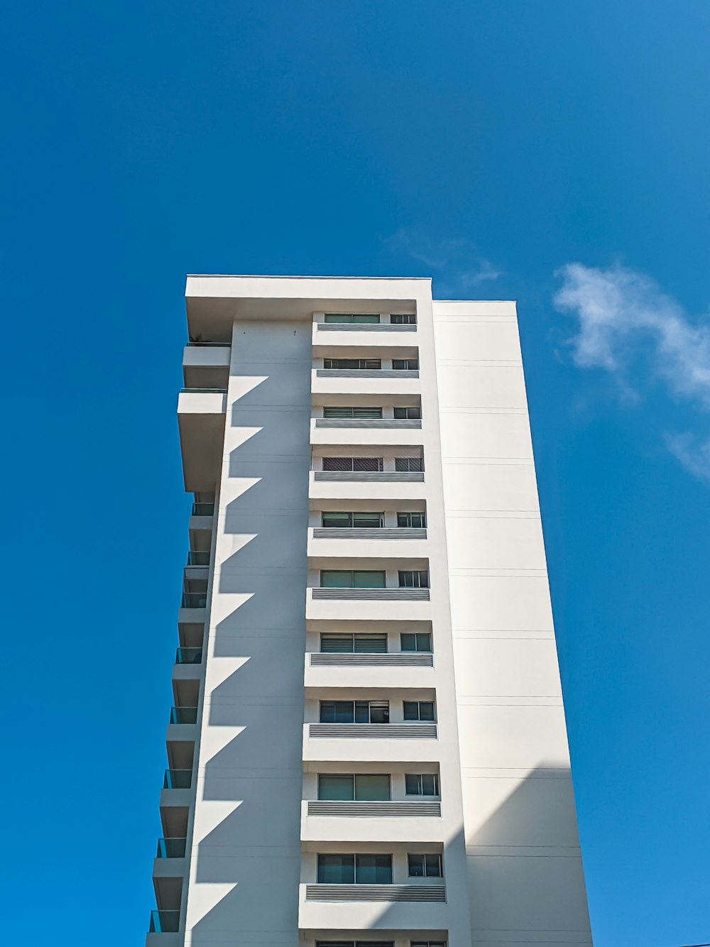 a tall white building with balconies against a blue sky