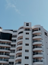 a tall white building with balconies and windows