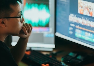 a man sitting in front of two computer monitors