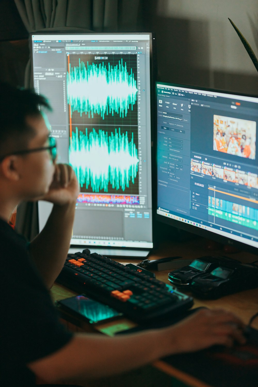 um homem sentado na frente de dois monitores de computador