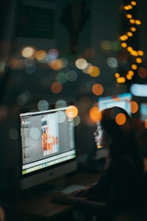 a woman sitting in front of a computer monitor