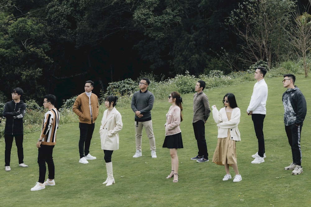 a group of people standing on top of a lush green field