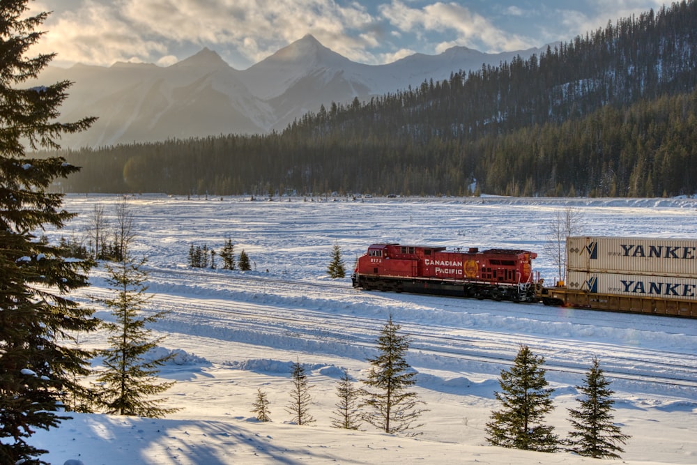 a red train traveling through a snow covered forest