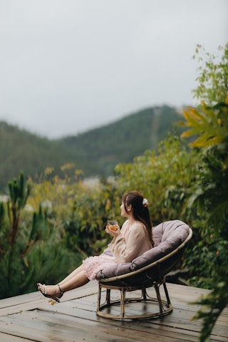 a woman sitting in a chair on top of a wooden deck