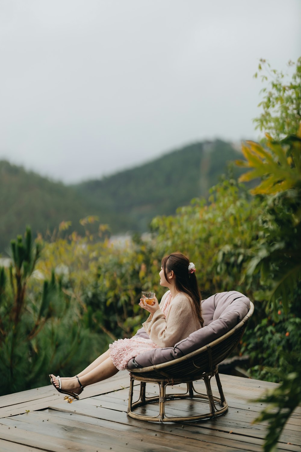 a woman sitting in a chair on top of a wooden deck