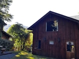 Cozy wooden house exterior surrounded by lush greenery under soft daylight.