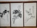 Three framed artworks feature traditional Chinese ink paintings depicting trees or plants with calligraphy accompanying each piece. The brushwork is expressive, with varying shades of black and gray creating depth and texture on the pale background.