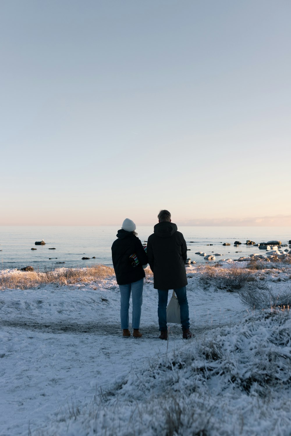 um par de pessoas em pé em cima de um campo coberto de neve