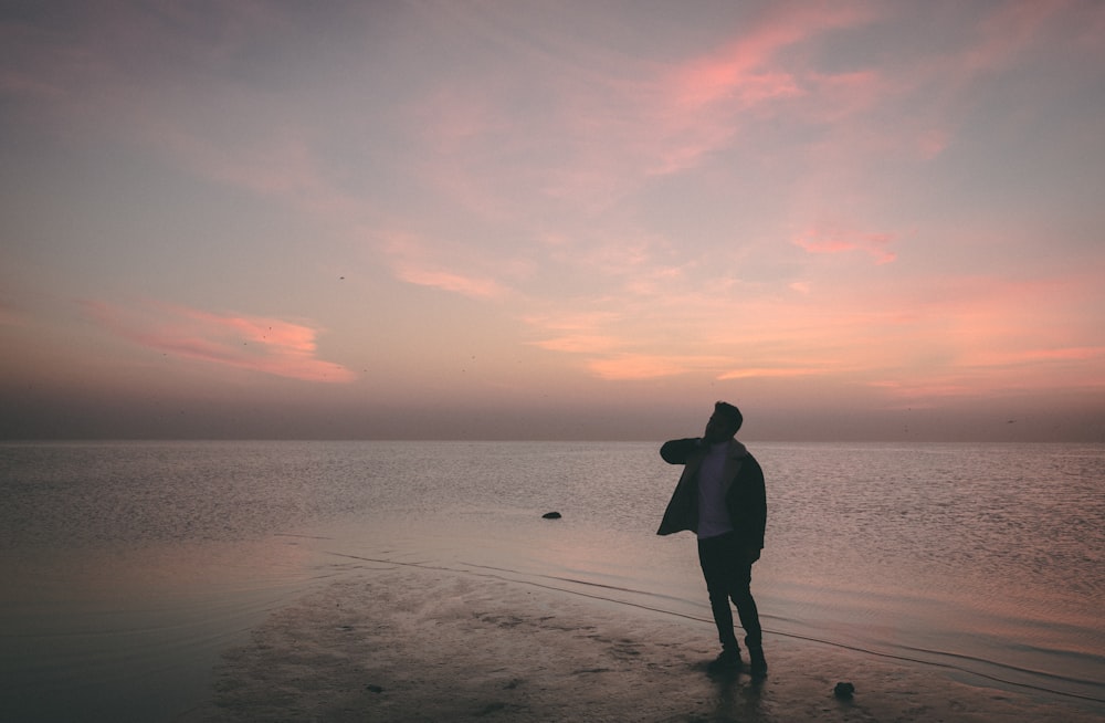 a man standing on a beach next to the ocean