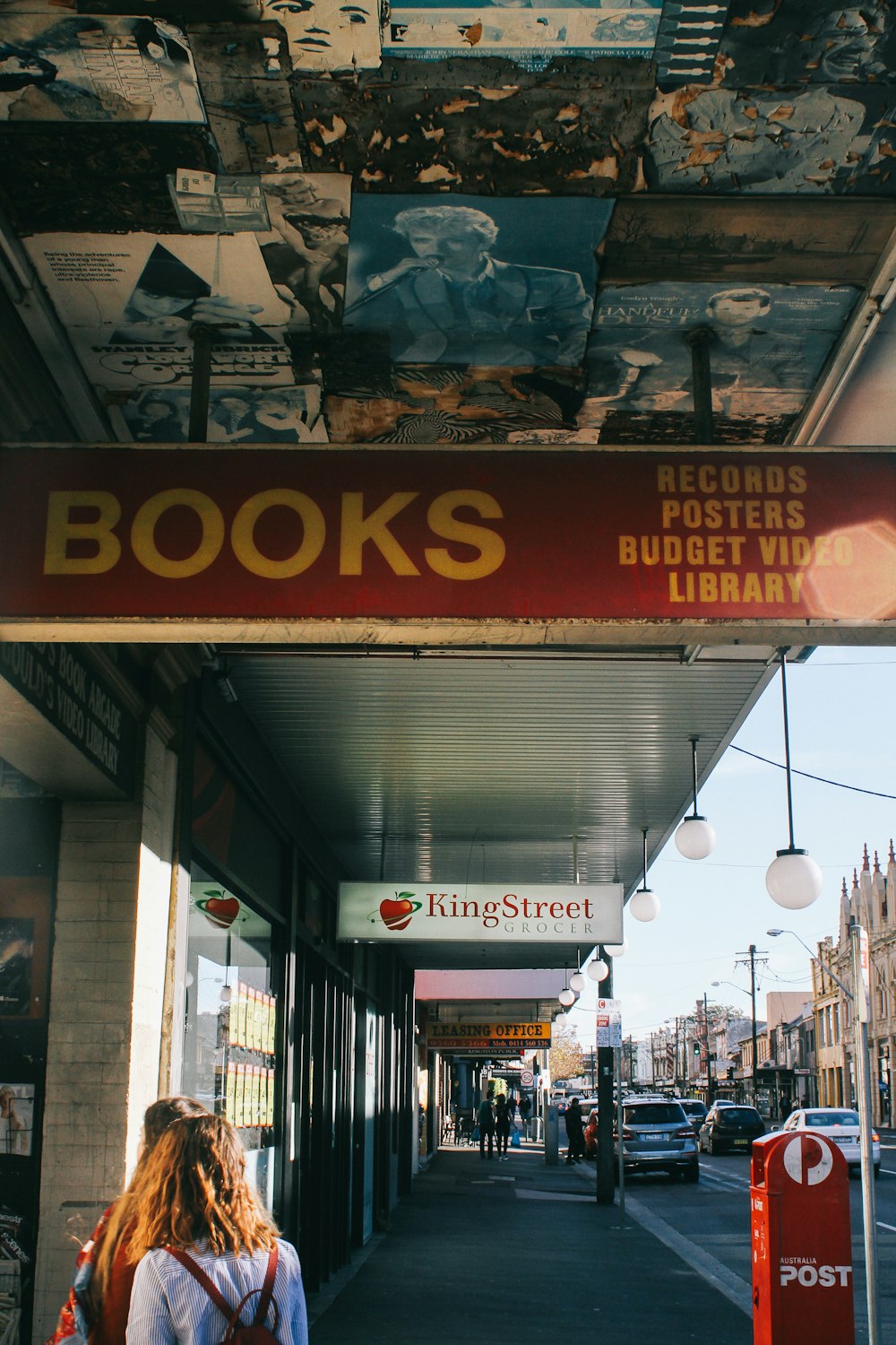 a woman walking down a street under a book store