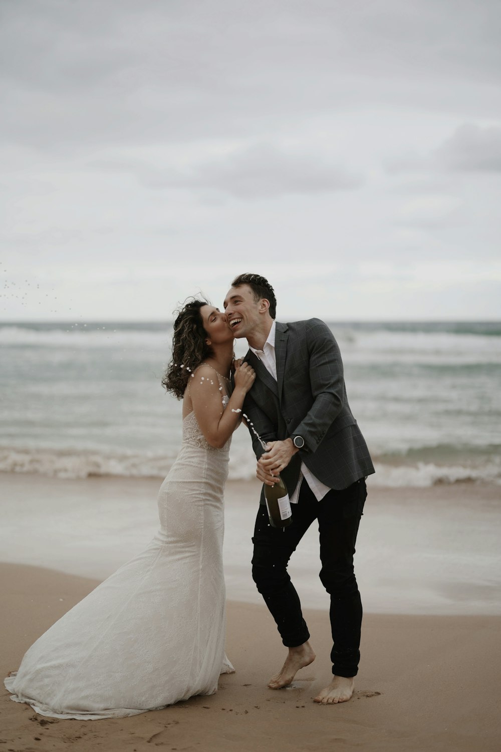 a newly married couple kissing on the beach