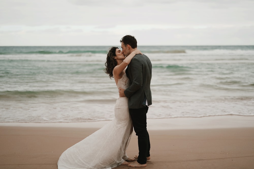 a bride and groom kissing on the beach