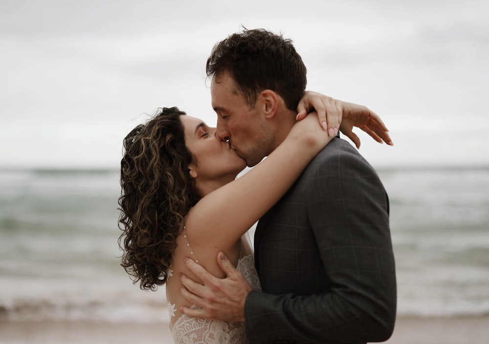 a man and a woman kissing on the beach