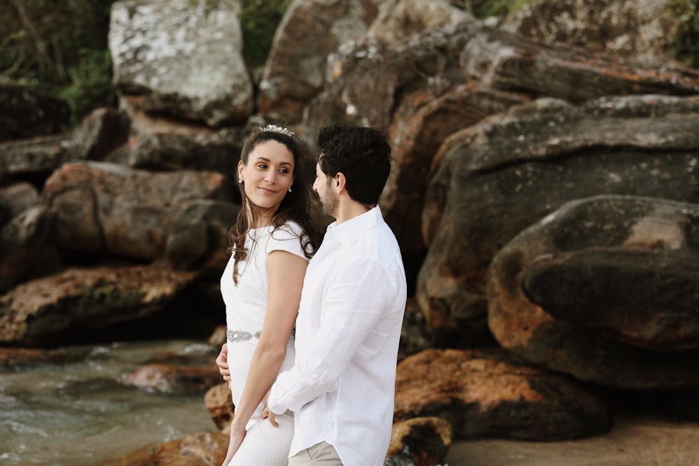 a man and woman standing next to each other near a river