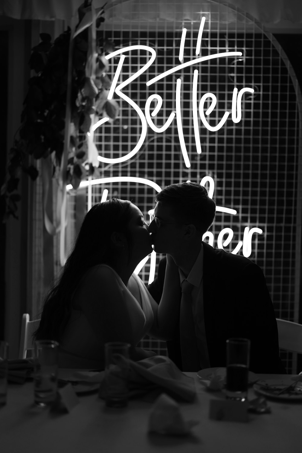 a man and woman kissing in front of a neon sign
