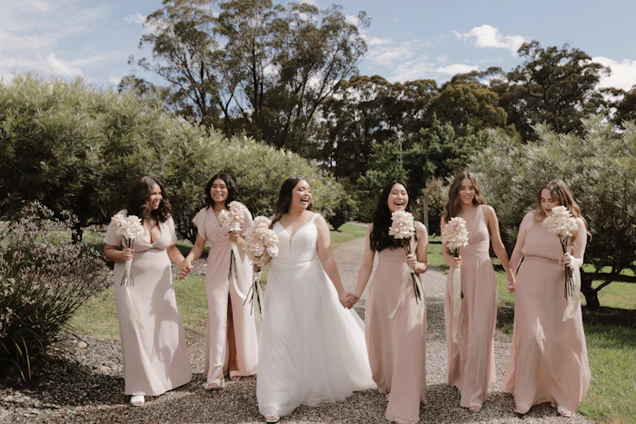 A bride walking with her bridesmaids in blush dresses