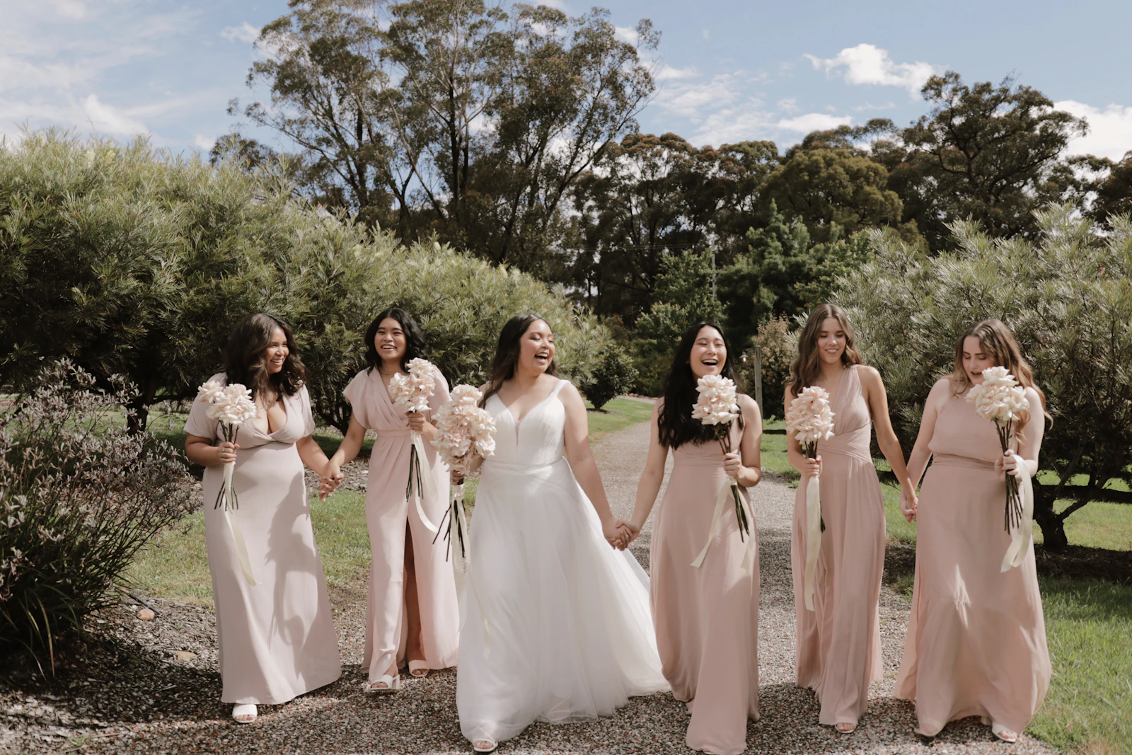 Bride and bridesmaids walking along a path in a garden