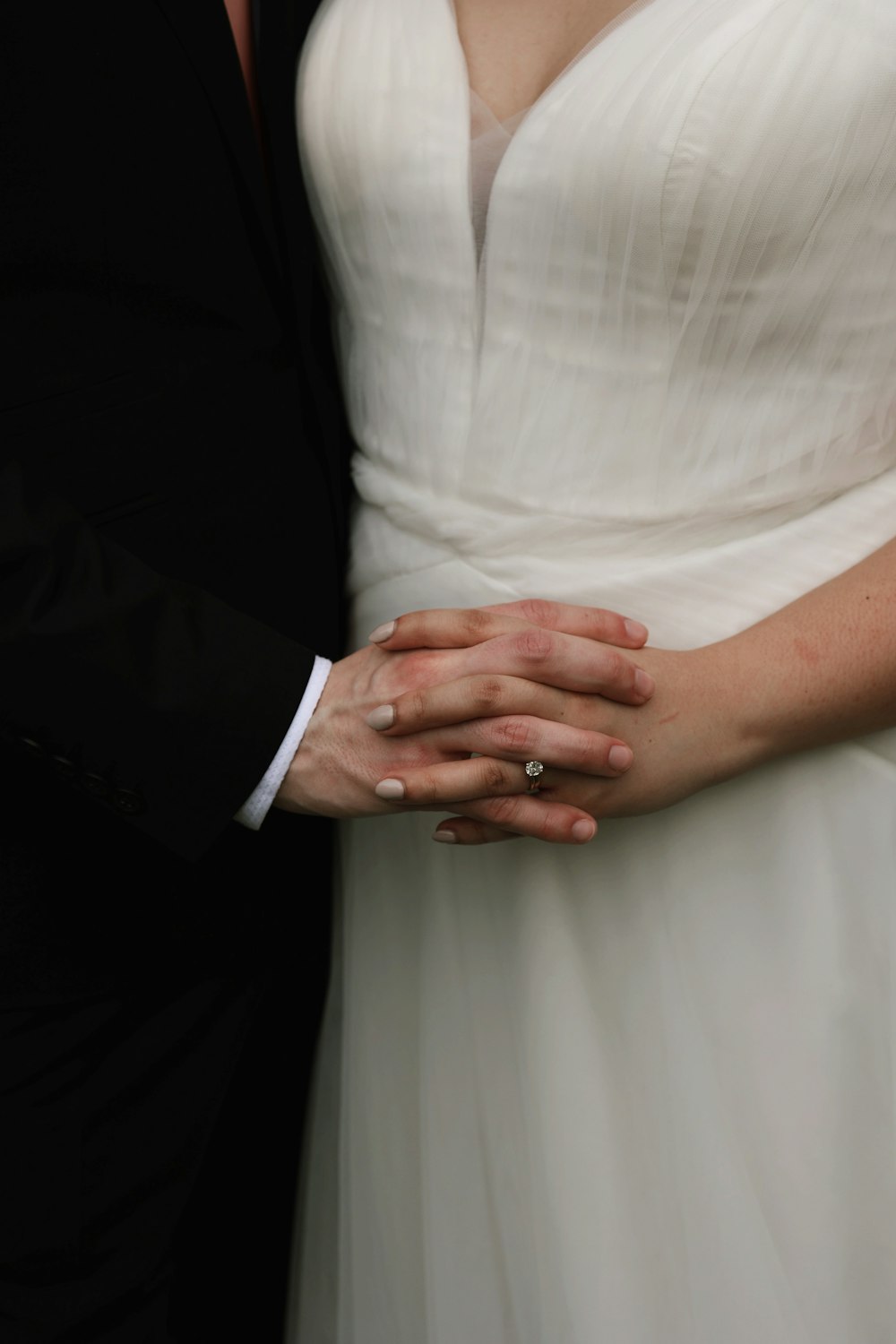 a close up of a bride and groom holding hands