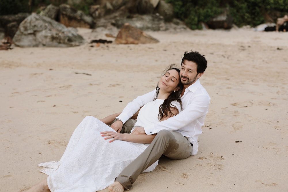 a man and woman sitting on the beach together