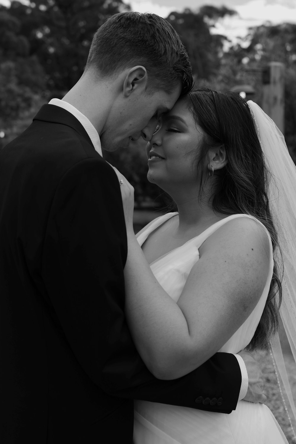 a bride and groom embracing each other in a black and white photo