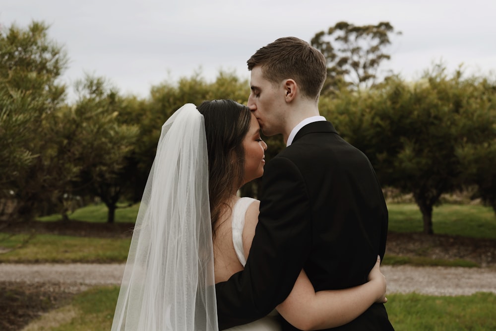 a bride and groom kissing in front of trees