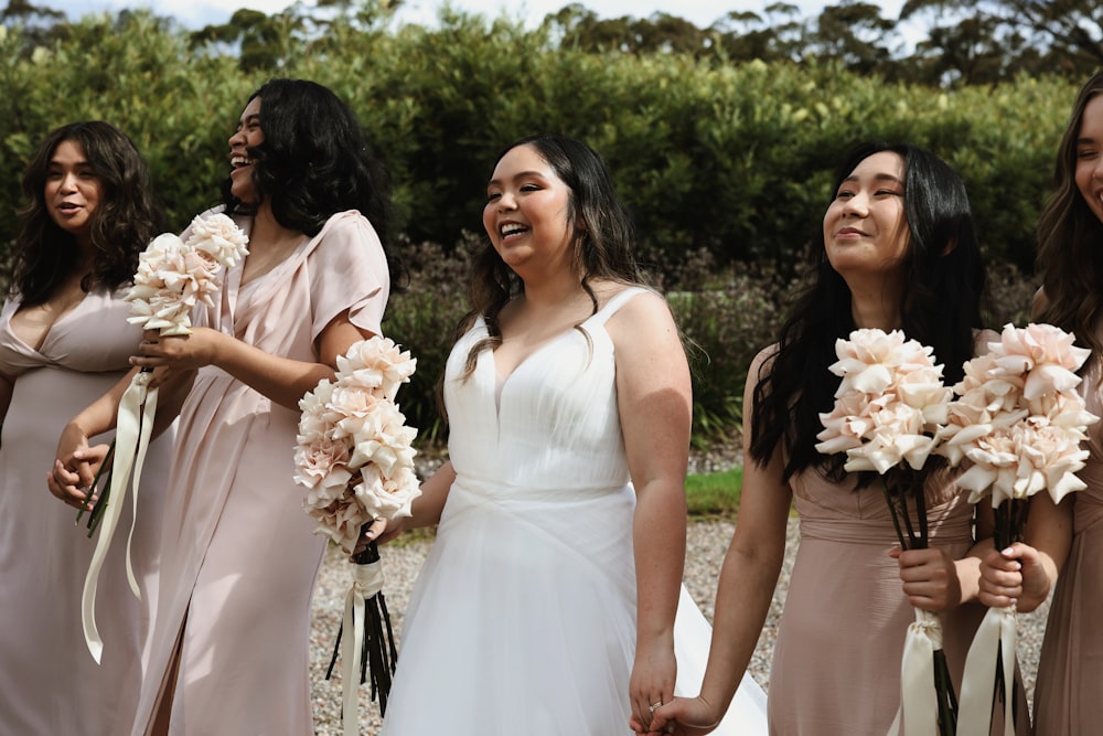 a group of women standing next to each other holding bouquets