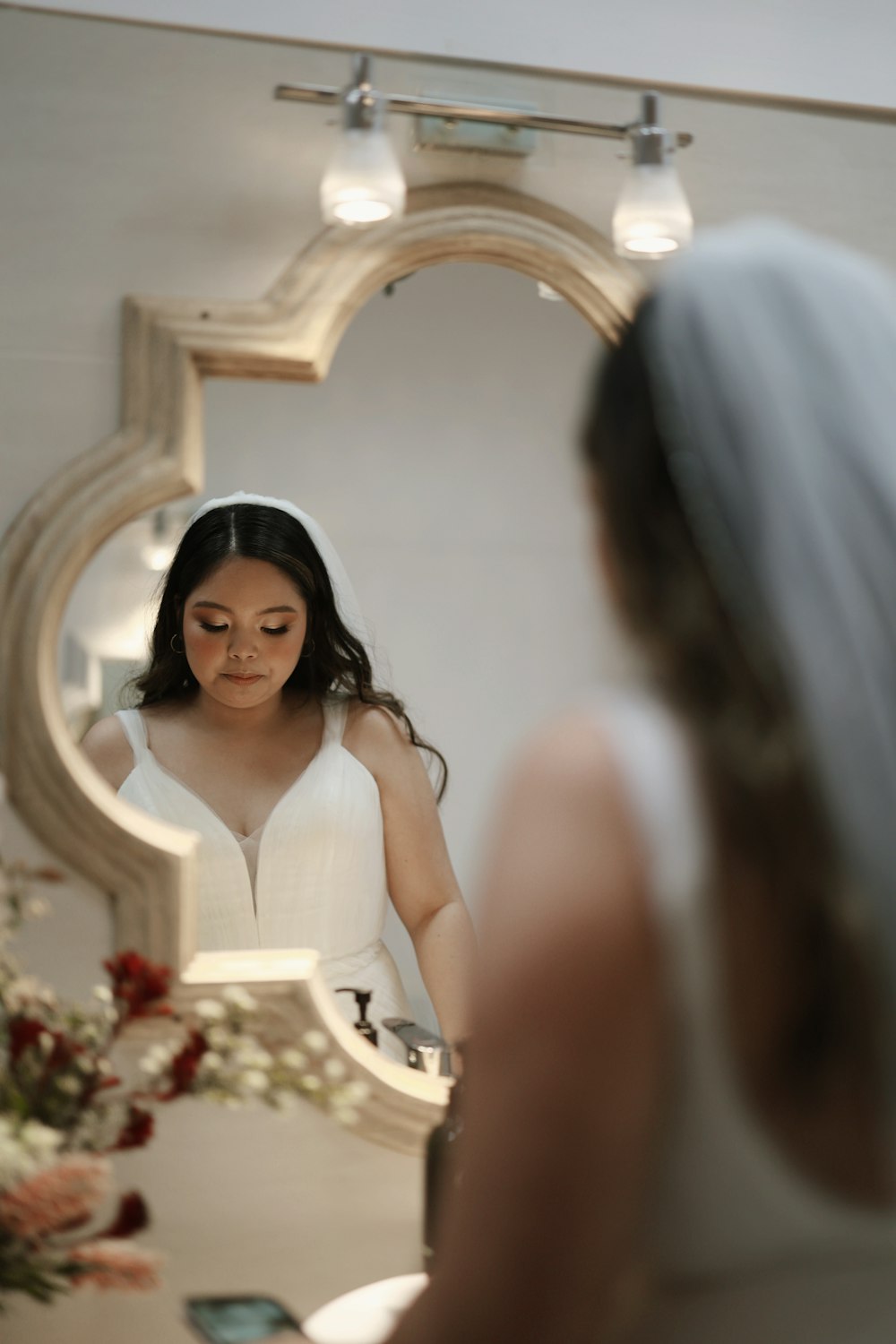 a woman in a wedding dress looking at her reflection in a mirror