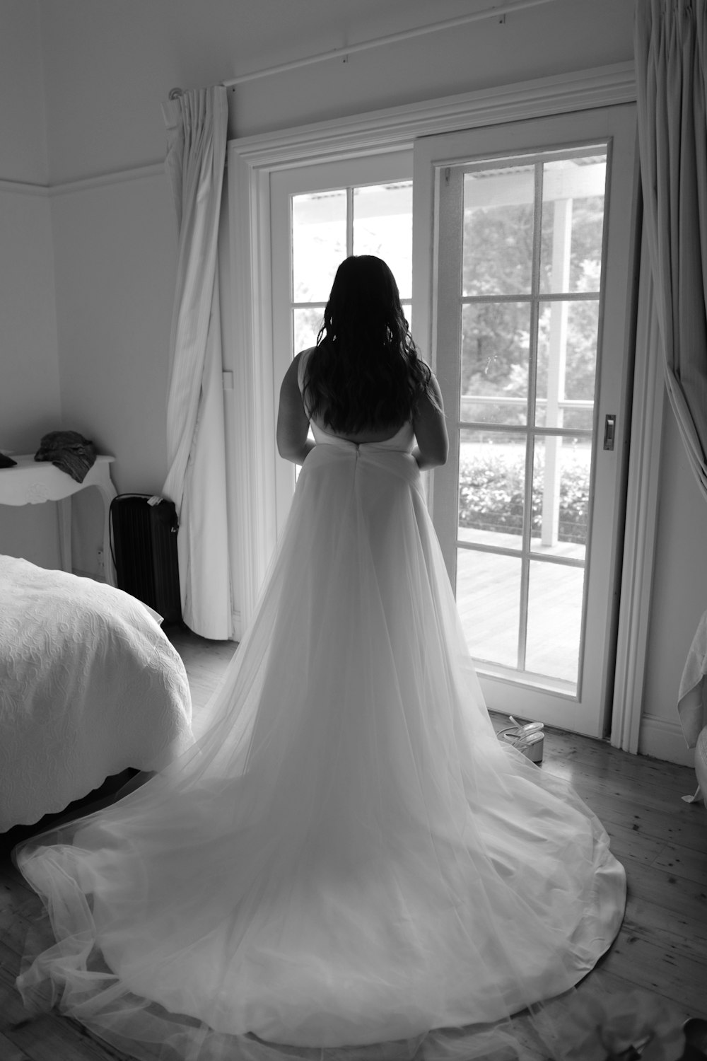 a woman in a wedding dress standing in front of a window