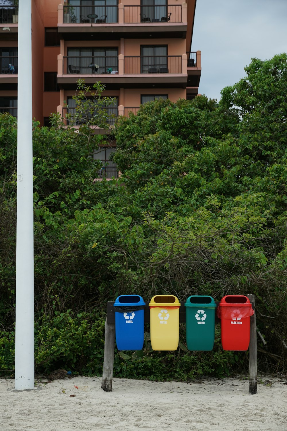 a row of trash cans sitting on top of a sandy beach