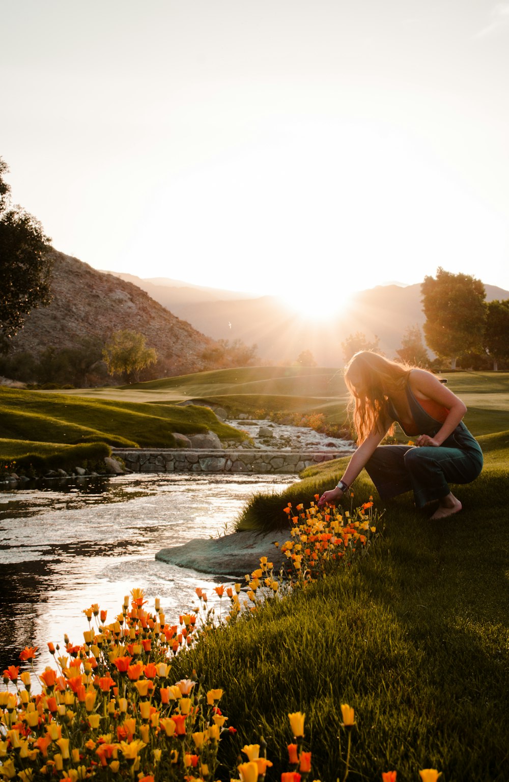 a woman kneeling down next to a river