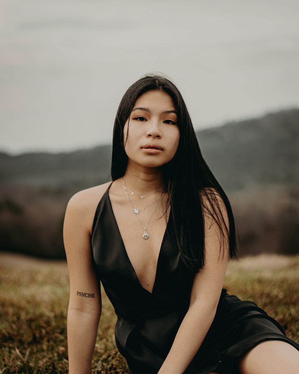 a woman in a black dress sitting in a field