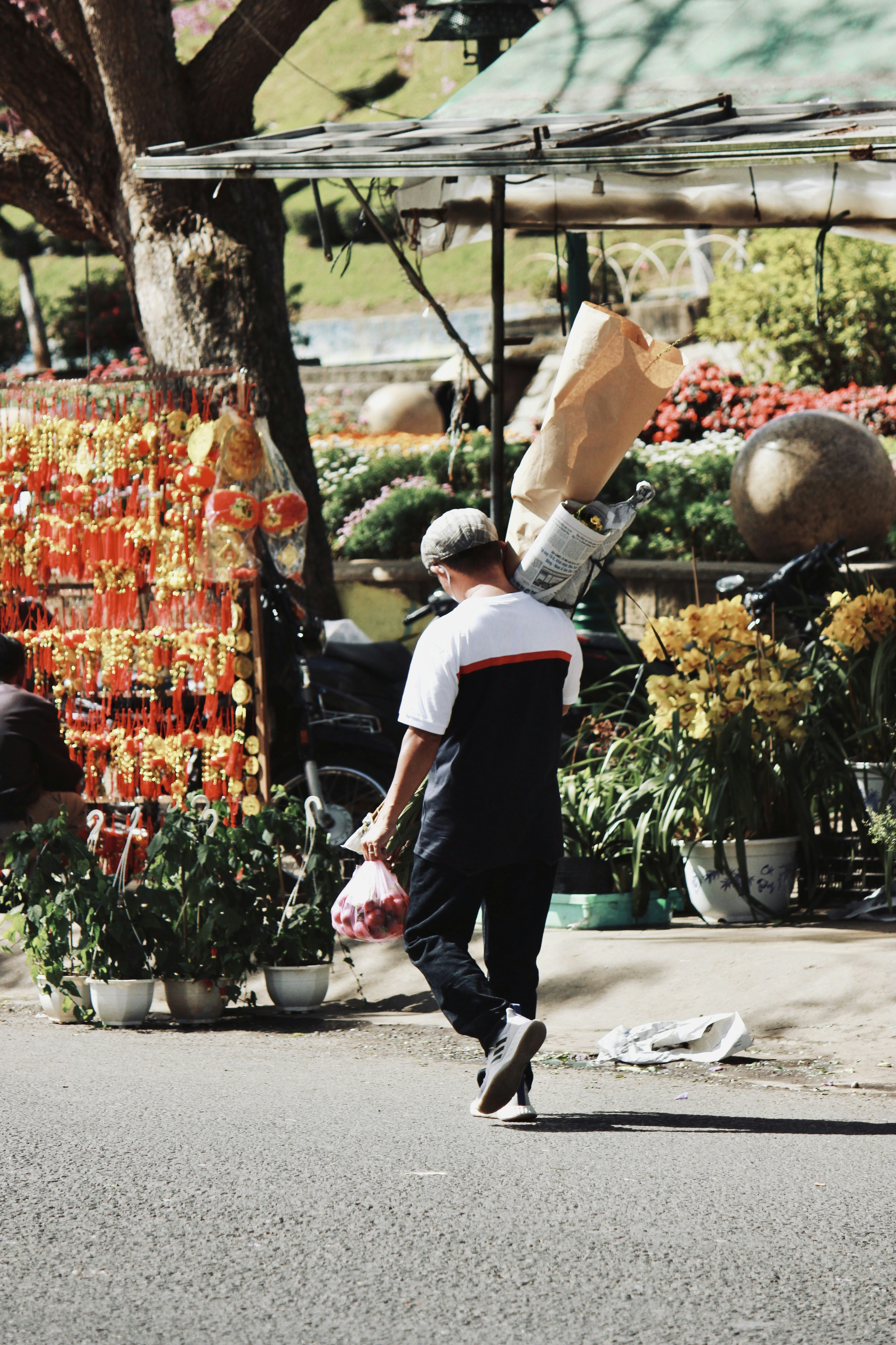 a man walking down a street past a flower shop
