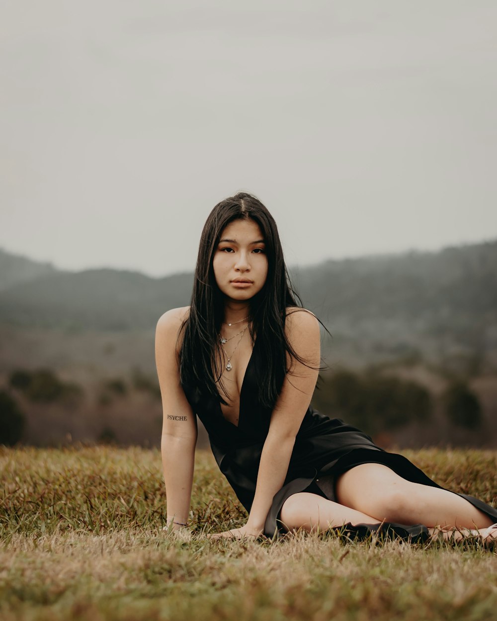 a woman in a black dress sitting in a field
