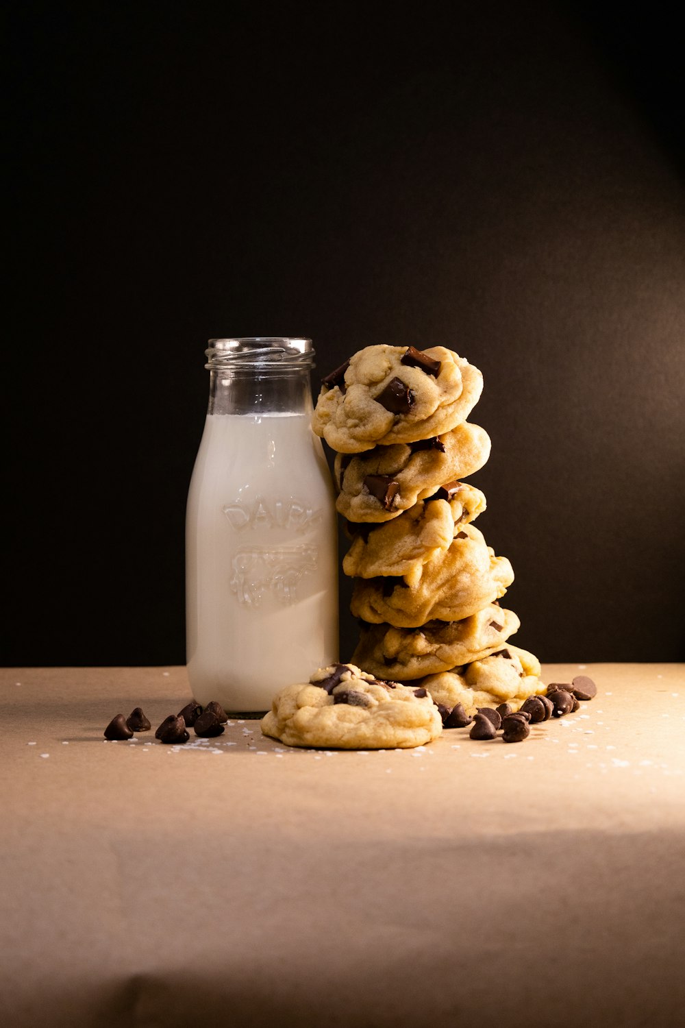 a stack of cookies next to a bottle of milk