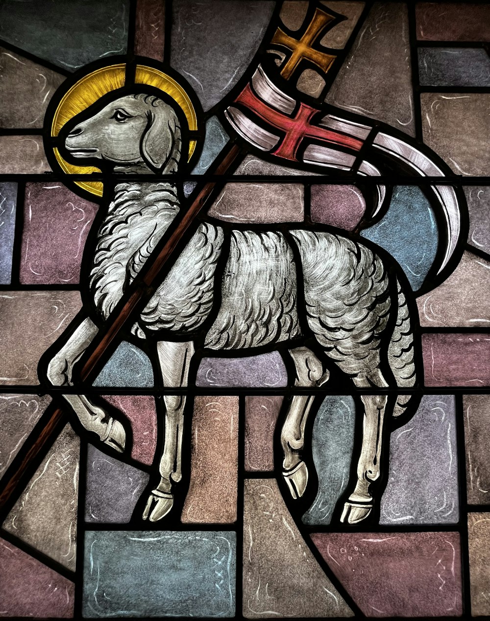 ein Buntglasfenster mit einem Schaf, das eine Flagge hält